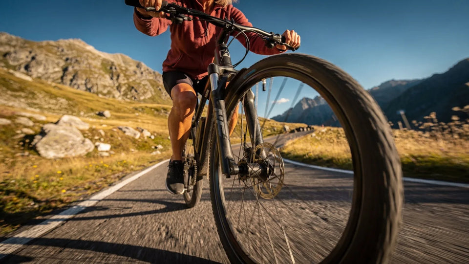 Radfahrerin um die 70 auf einer Passstraße, im Sommer, im frühen Morgenlicht