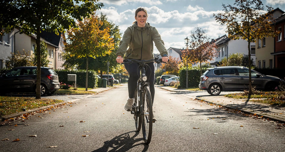 Radfahrerin fährt im Herbst auf einer Wohnstraße auf den Betrachter zu