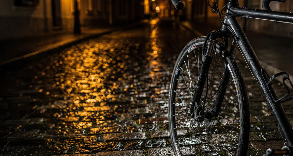 Vorderrad eines Fahrrads auf nassem Kopfsteinpflaster bei Nacht