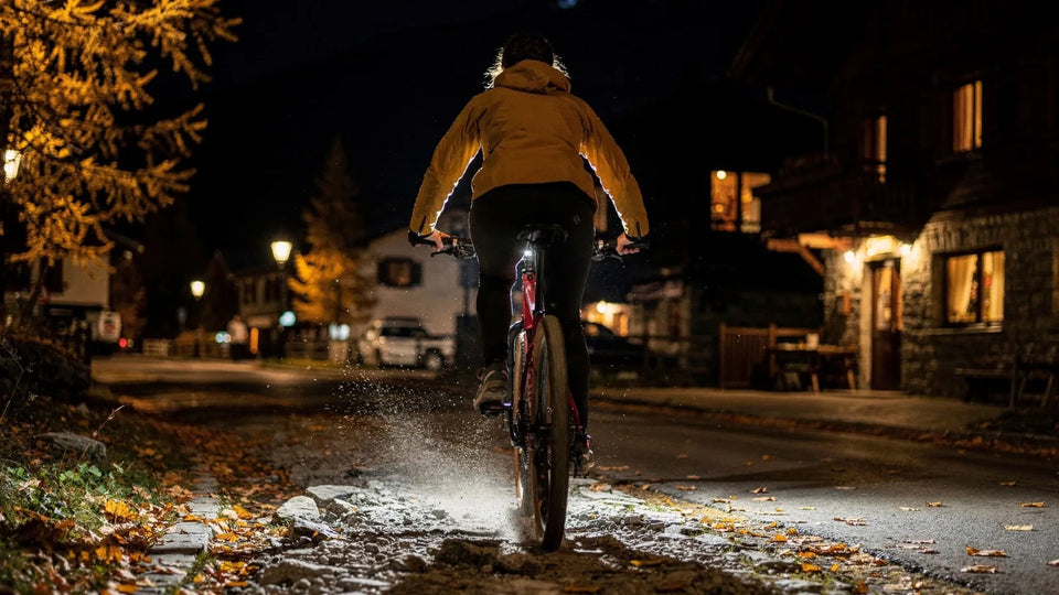 Radfahrer abends in einer Bergstadt, im Herbst, im Licht von Fahrradlicht und Laternen